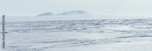 Arctic landscape. View of the snow-covered tundra and snow-capped mountains. Cold weather. The harsh climate of the polar region. Nature of the Arctic. Wide panorama. Great for background.
