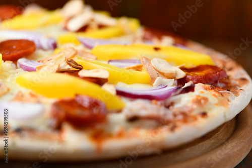 Pizza with chorizo ​​sausage, mozzarella cheese, yellow pepper and black olives. Rustic wooden background. Soft focus.	