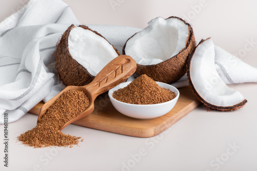 Organic coconut sugar in a wooden scoop. Natural sweetener, Healthy alternative to Refined White Sugar. Fresh coconut with coconut sugar.