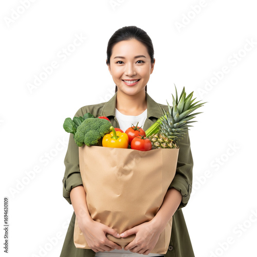 Asian woman holding a grocery bag filled with fresh produce against black background