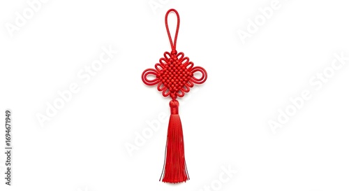 Red Chinese knot meticulously crafted featuring an intricate loop and hanging tassel against a stark white backdrop
