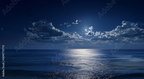 Fototapeta Naklejka Na Ścianę i Meble -  a vast expanse of dark blue sea under the night sky, illuminated by moonlight and stars. the water reflects the silver light, creating an atmosphere reminiscent of a serene ocean landscape