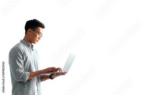 Standing Southeast Asian Man Typing on Laptop with Focused Expression, Side-Angled Office Style, Isolated on Transparent Background (2)