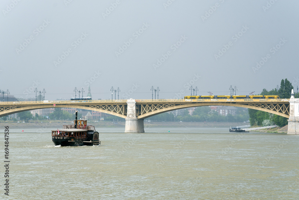Obraz premium Vintage boat on the river against bridge