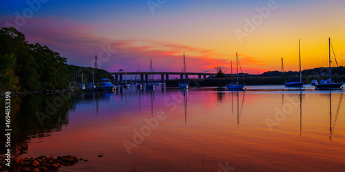 Fototapeta Naklejka Na Ścianę i Meble -  Seascape at sunset with moored boats and yachts at Old Lyme Marina in Connecticut, a vibrant autumn landscape of New England’s landmark marina