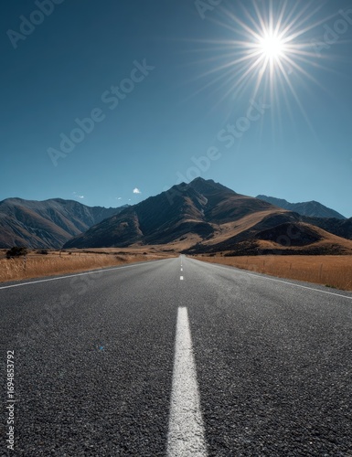 Open road stretching to mountains under a bright sun