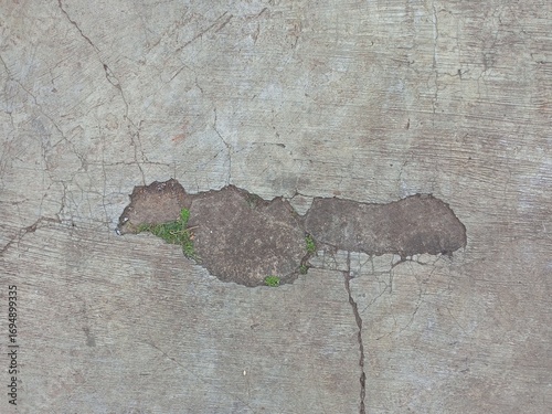 Broken Concrete Pavement with a Pothole and Weeds