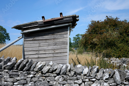 wooden hut with Dry stone wall in foreground in summer