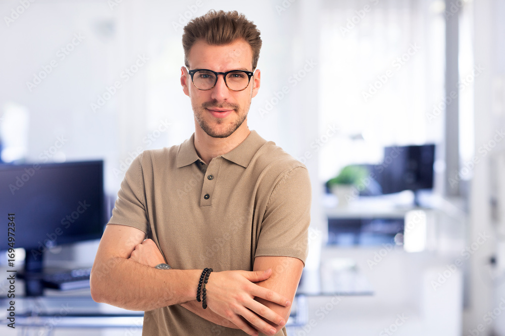 Fototapeta premium Confident young man standing at the office and looking at camera