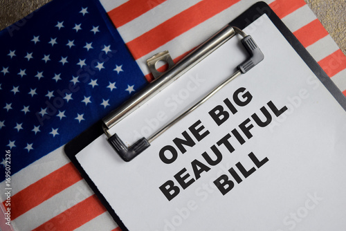 Concept of one big beautiful bill with the United States flag write on clipboard isolated on Wooden Table.