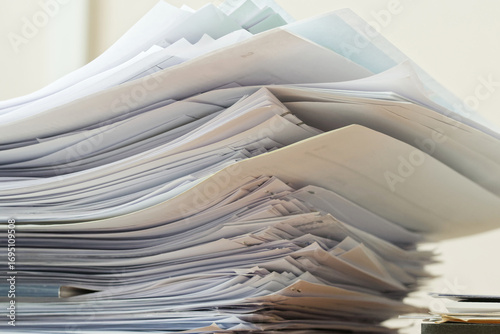 Large messy stack of paper documents piled up in an office, symbol of bureaucracy, archive and paperwork overload. Photo