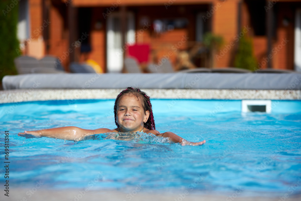 Obraz premium Girl enjoying a playful swim in the pool