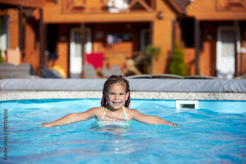Girl enjoys swimming in the pool on a sunny day