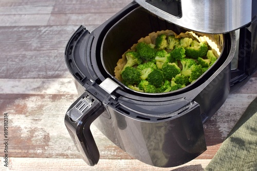 Black deep fryer with broccoli inside. Deep fryer paper.