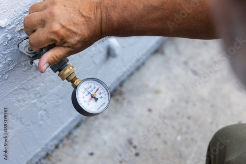 A home inspector checking water pressure with a water pressure meter