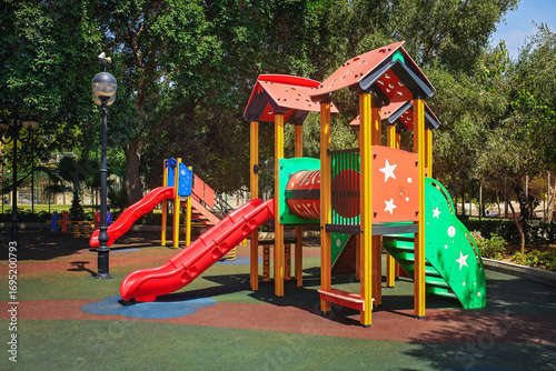 Wallpaper Mural Colorful playground with slides and play structures on soft rubber flooring in a sunny park among trees. Torontodigital.ca