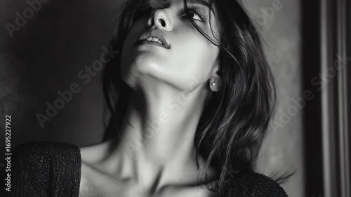 A black and white portrait of a beautiful Indian girl with long straight hair, wearing a v-neck top, gazing slightly to her right
