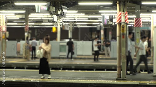 TOKYO, JAPAN - JUL 2025 : Crowded train station in Tokyo. Commuters, people and traffic during rush hour. Daily urban life, business, and public transportation in a busy metropolis. Time lapse shot.