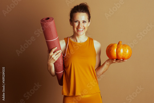 Smiling Woman with Yoga Mat and Autumn Pumpkin