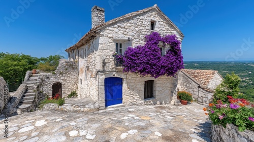 Charming Stone House with Purple Flowers and Clear Blue Sky