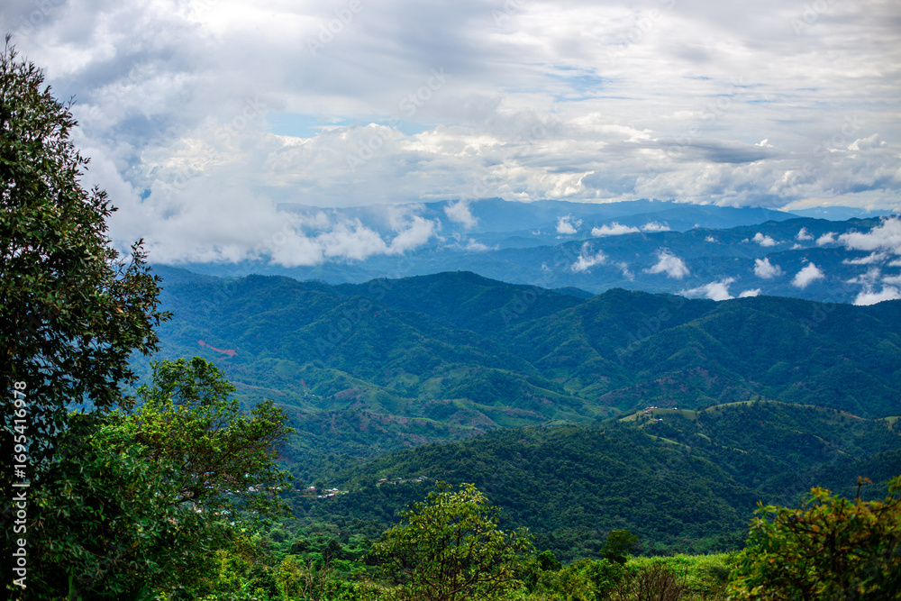 Obraz premium A wide-angle view of the natural scenery of the large mountains, with the wind blowing the mist and some rain falling on the trees. Happiness during the travel to study the resources.