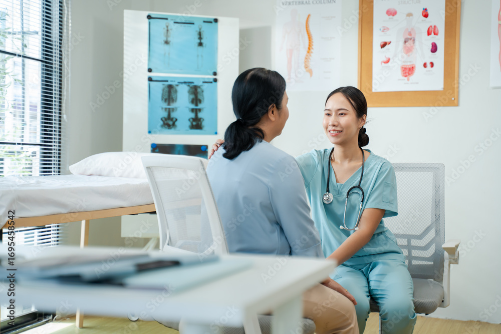 Obraz premium Asian nurse supporting senior woman patient in wheelchair during checkup at hospital or rehabilitation clinic.Smiling caregiver assisting elderly woman with friendly and supportive healthcare service