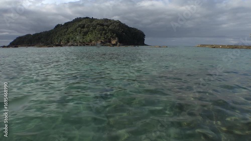 View of Goat Island from just above water level with sea surface in foreground. Location: Goat Island New Zealand