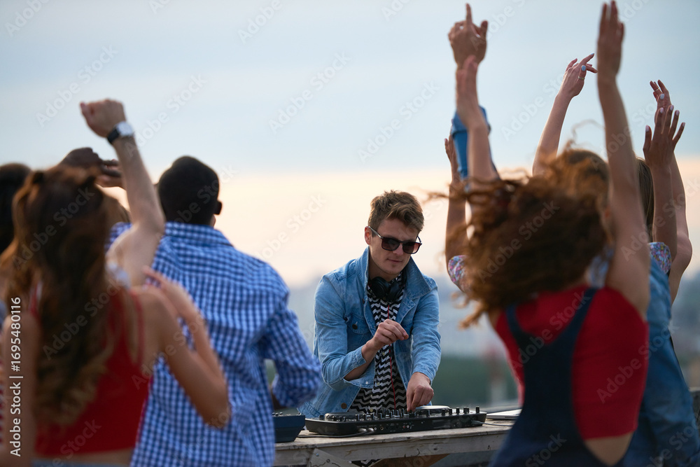 © pressmaster - Group of multiethnic young adults dancing outdoors while Caucasian young adult man DJ operating mixing console, people raising hands and enjoying music at rooftop party © pressmaster - Group of multiethnic young adults dancing outdoors while Caucasian young adult man DJ operating mixing console, people raising hands and enjoying music at rooftop party