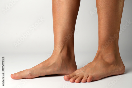 Barefoot woman's feet from the side, on a white background