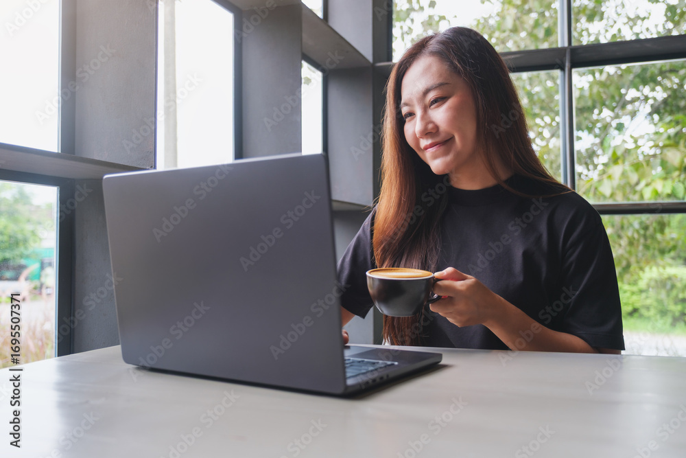 Fototapeta premium Portrait image of a woman working on laptop computer while drinking coffee in cafe