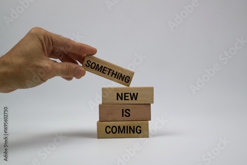 A hand arranges wooden blocks to display the message 