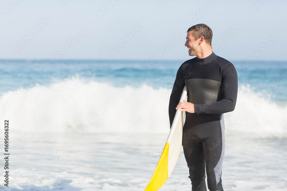 Fototapeta premium surfboard leaning on sandy beach near waves breaking on shoreline under blue sky