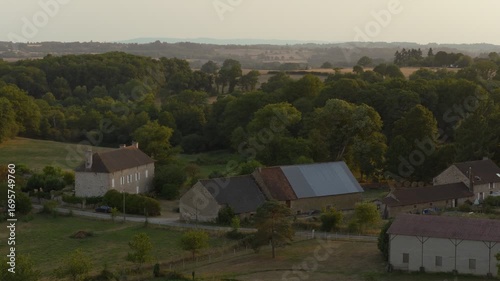 Wallpaper Mural Aerial view of a countryside village with stone houses, barns, and winding roads glowing in warm sunset light. Torontodigital.ca