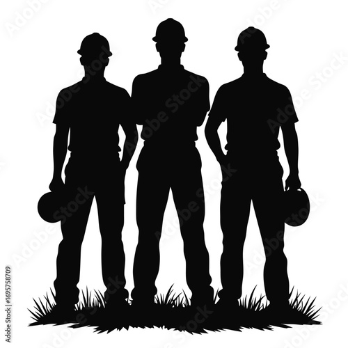 Silhouette of three men wearing hard hats on grass
