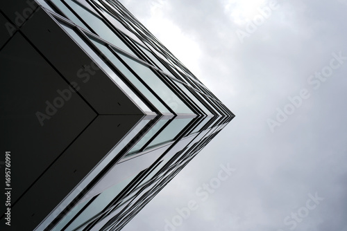 Obraz na plátně Abstract view of modern glass building corner against cloudy sky, highlighting s