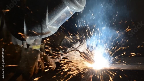 An industrial worker welding hot steel, the manufacturing work creating a flame with smoke and heat inside the factory