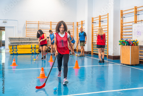 Εκτύπωση καμβά Female athlete dribbling ball during floor hockey training in gym