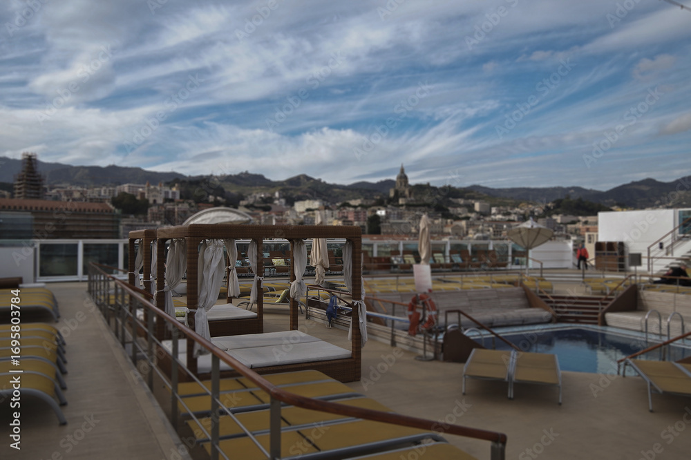 Fototapeta premium Pooldeck or swimmingpool with sun deck on modern cruiseship or cruise ship liner with elegant lounge furniture deck chairs and rattan sun beds loungers