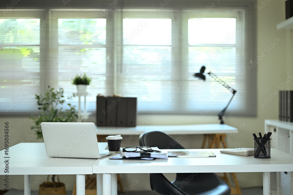 Fototapeta premium Modern office desk with laptop, coffee cup, and documents in bright workspace
