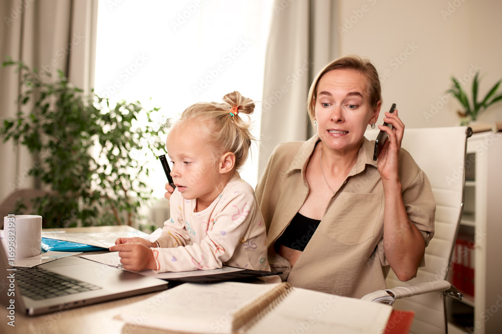 Fototapeta premium Mother working from home while caring for her young child