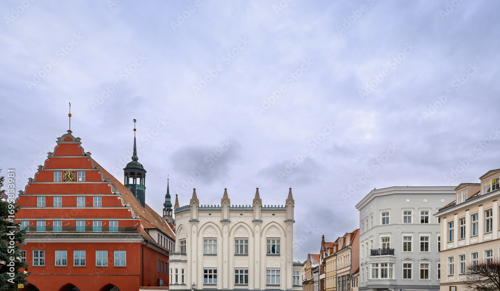 Fototapeta premium Barock überformtes gotisches Altstadtensemble mit Rathaus und Ziertürmchen am Marktplatz von Greifswald - Inschriften retuschiert