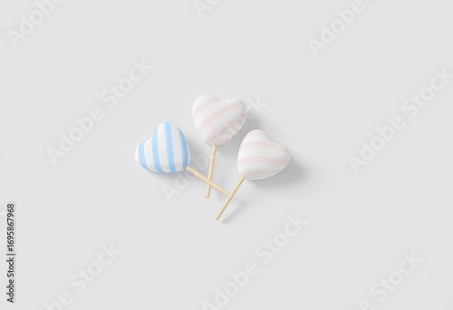 Three pastel heart-shaped lollipops on sticks, light gray background