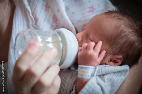 A gentle moment unfolds as a parent feeds their newborn with a bottle in a warm, comfortable space. Soft lighting highlights the bond shared during this nurturing activity.