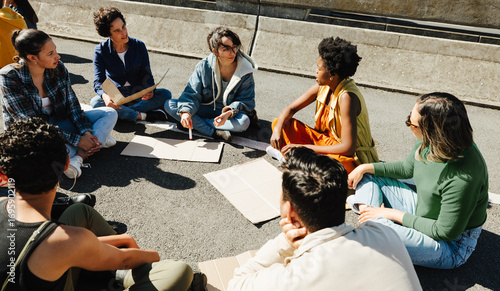 Obraz na plátně Group of young adults discussing social issues outdoors in a lively gathering