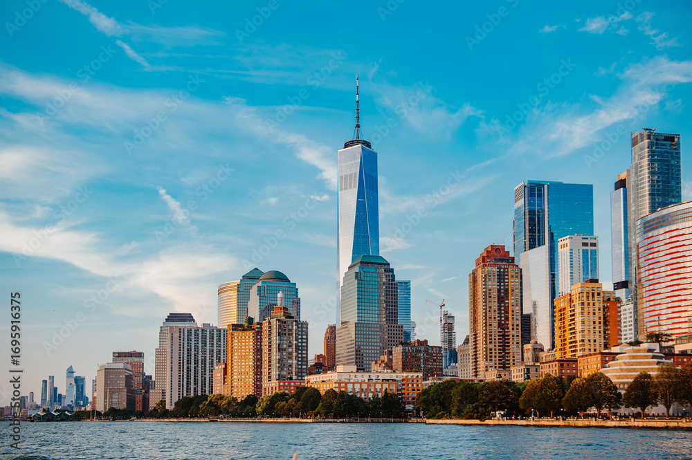 Obraz premium Manhattan skyline with One World Trade Center view. Manhattan skyline with One World Trade Center under a clear blue sky, showcasing vibrant urban life.