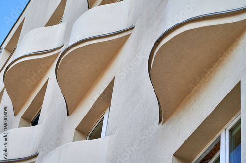 Curved white balconies of a modern residential building in Gdynia, Poland, showcasing sleek and minimalist architectural design against a clear blue sky.