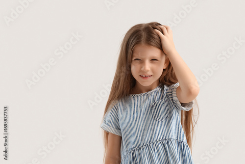 Photos Little girl with pediculosis scratching her head on light background