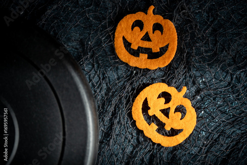 Dumbbell barbell weight plate and spooky Halloween pumpkins decorations. Healthy fitness lifestyle composition with copy space. Gym workout, sport training concept for autumn, fall season.