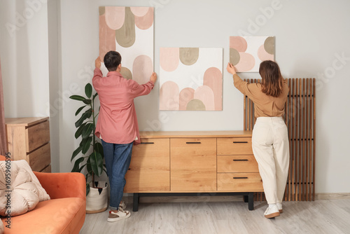 Young couple hanging painti...