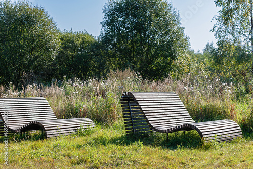 Fototapeta Naklejka Na Ścianę i Meble -  Wooden deck chair lounger in natural outdoor park relaxation area